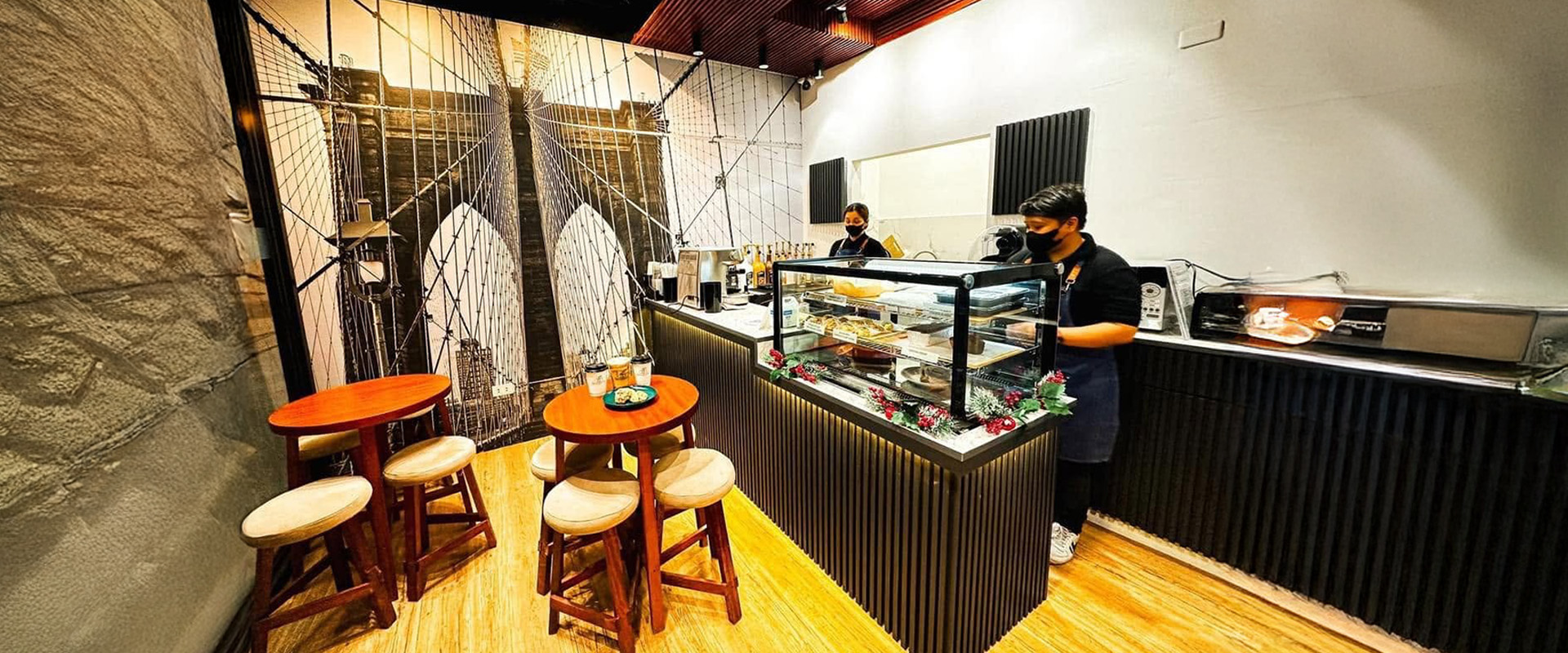 Inside the cafe: the Brooklyn Bridge mural wall, wooden stools and the pastry counter