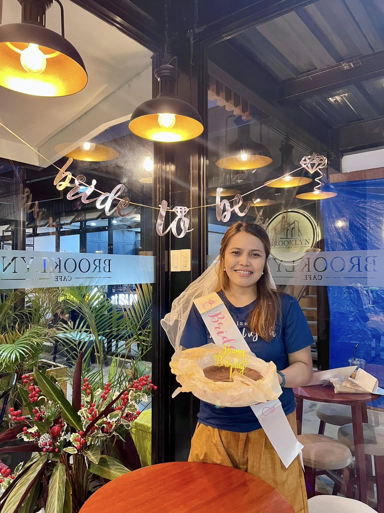 A guest of honour with a bride-to-be sash and a cake at the cafe entrance