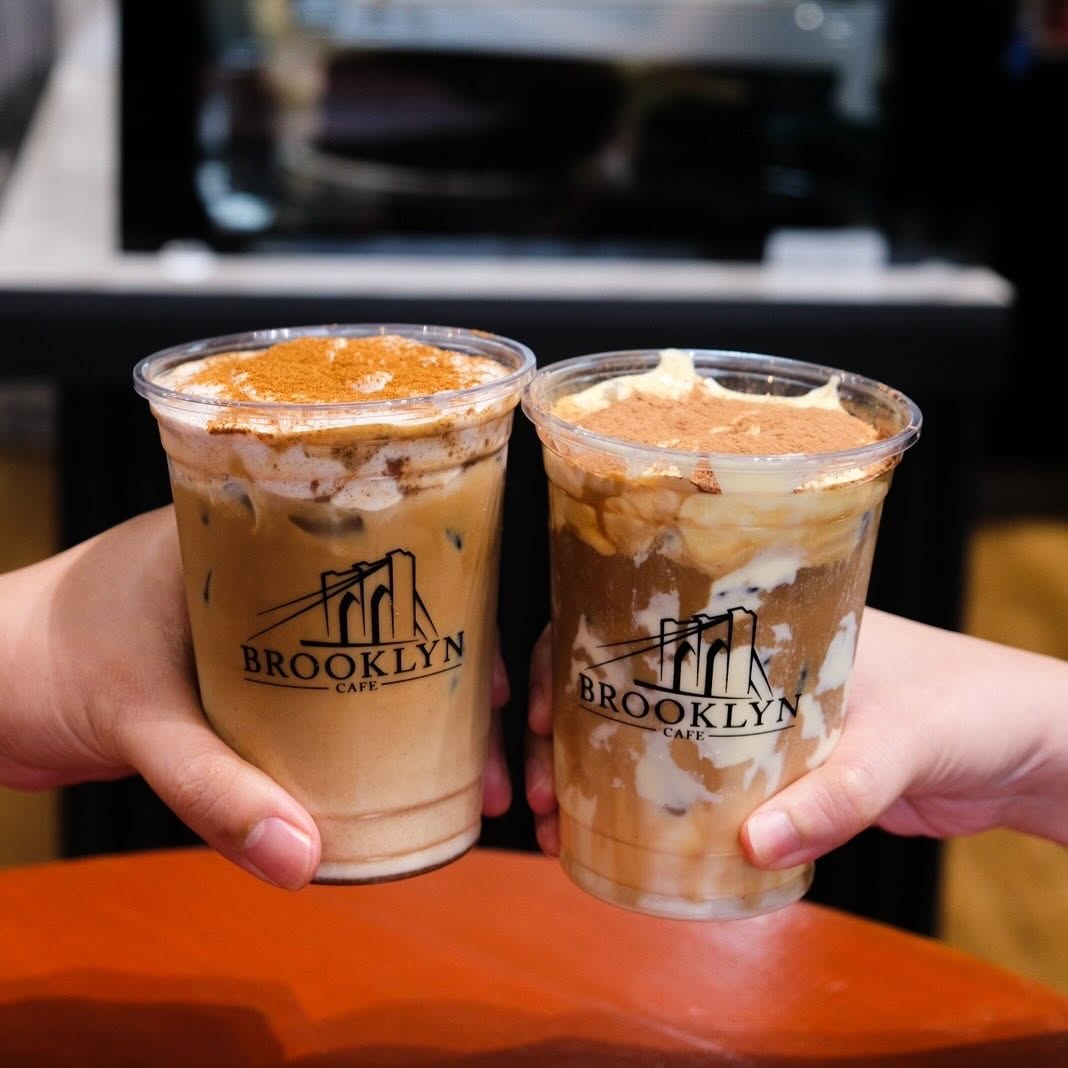 Two iced coffees topped with cream and dusted cinnamon